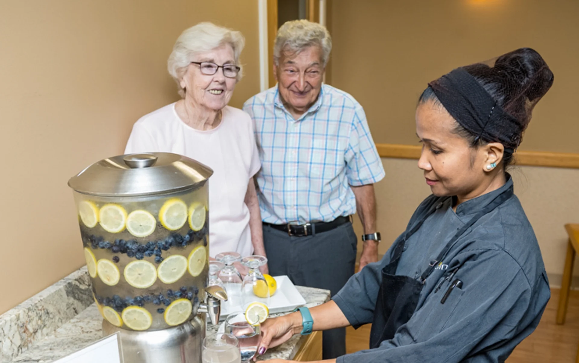 two residents getting a refreshment from a kitchen employee